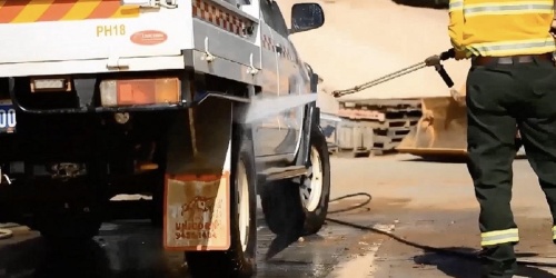 Person spraying down a DBCA vehicle using a high-pressure hose