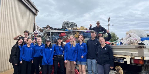 A group of people standing next to a ute full of marine debris