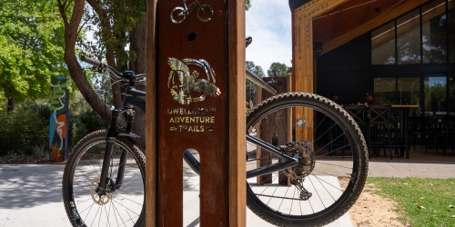 A mountain bike hangs on a bike rack with a Dwellingup Adventure Trails logo on it.