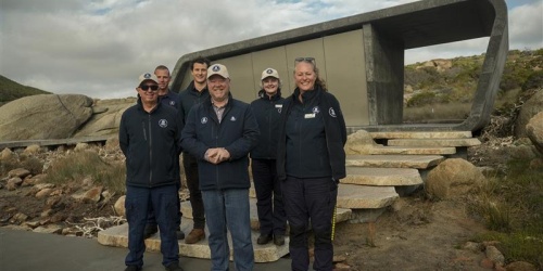 A group of people stand in front of a new toilet facility in a park.