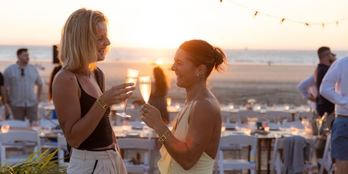 Two women clinking glasses at a festival