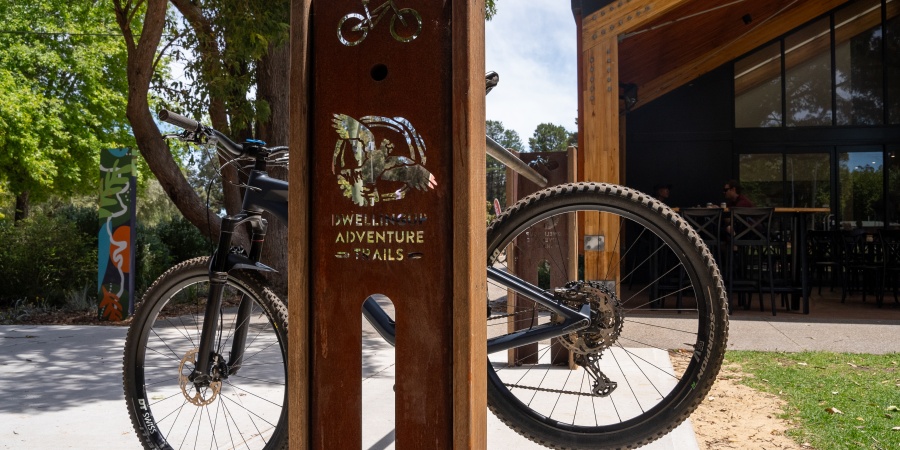 A mountain bike hangs on a bike rack with a Dwellingup Adventure Trails logo on it.