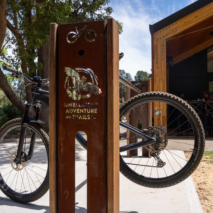 A mountain bike hangs on a bike rack with a Dwellingup Adventure Trails logo on it.