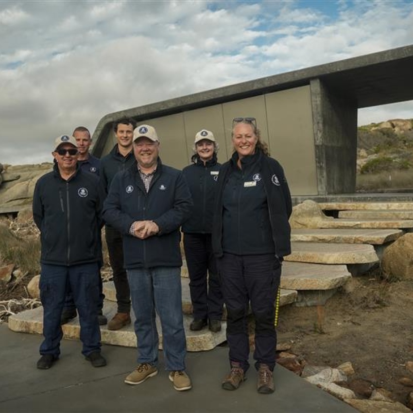 A group of people stand in front of a new toilet facility in a park.