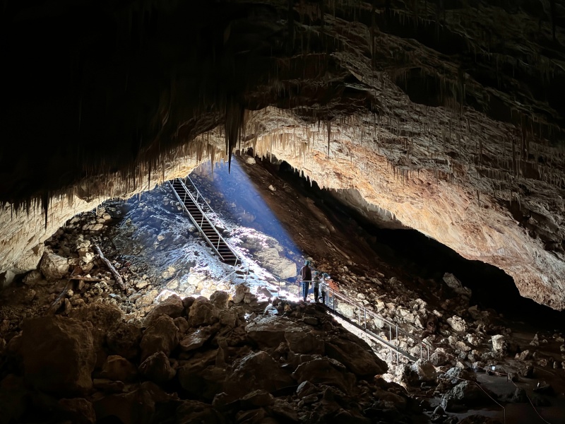 People standing in a large cave with sunlight streaming through