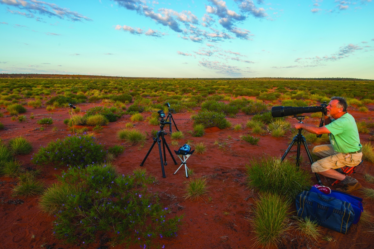Jiri looking through a camera with the desert in the background