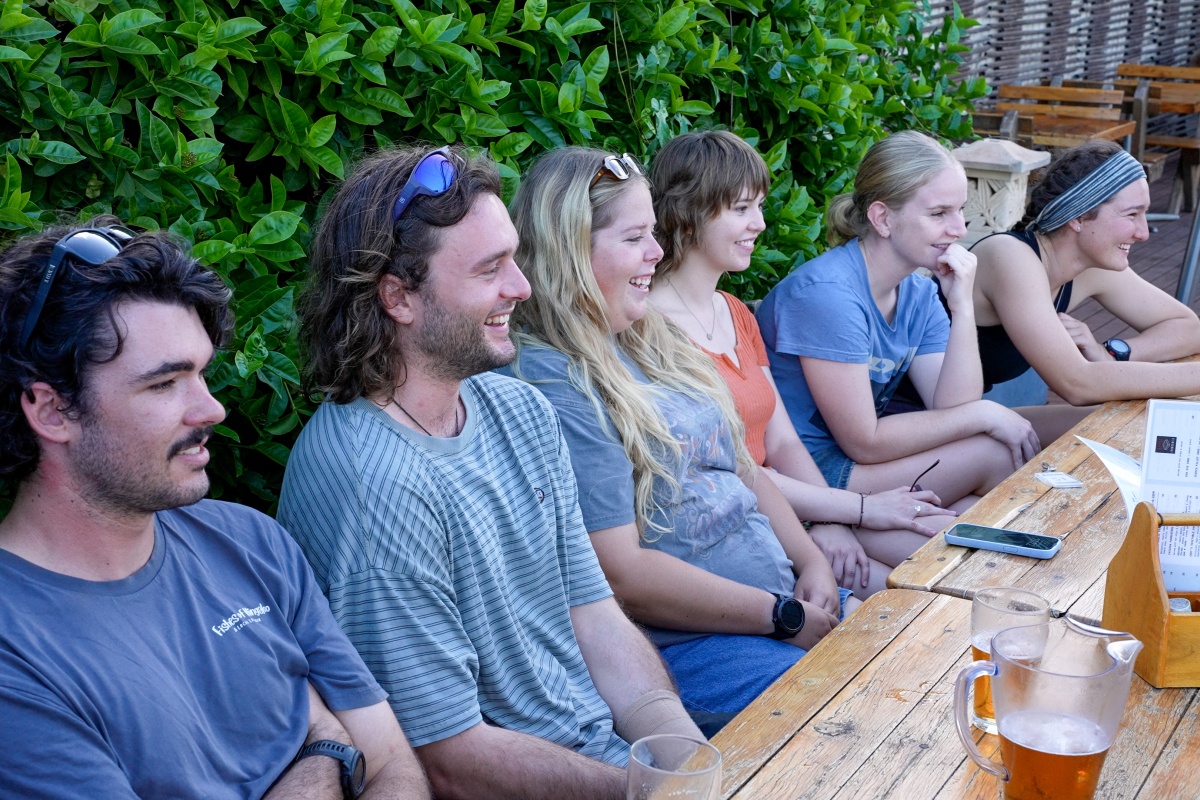 2 men and 3 women sit at a table smiling as part of the graduate program.