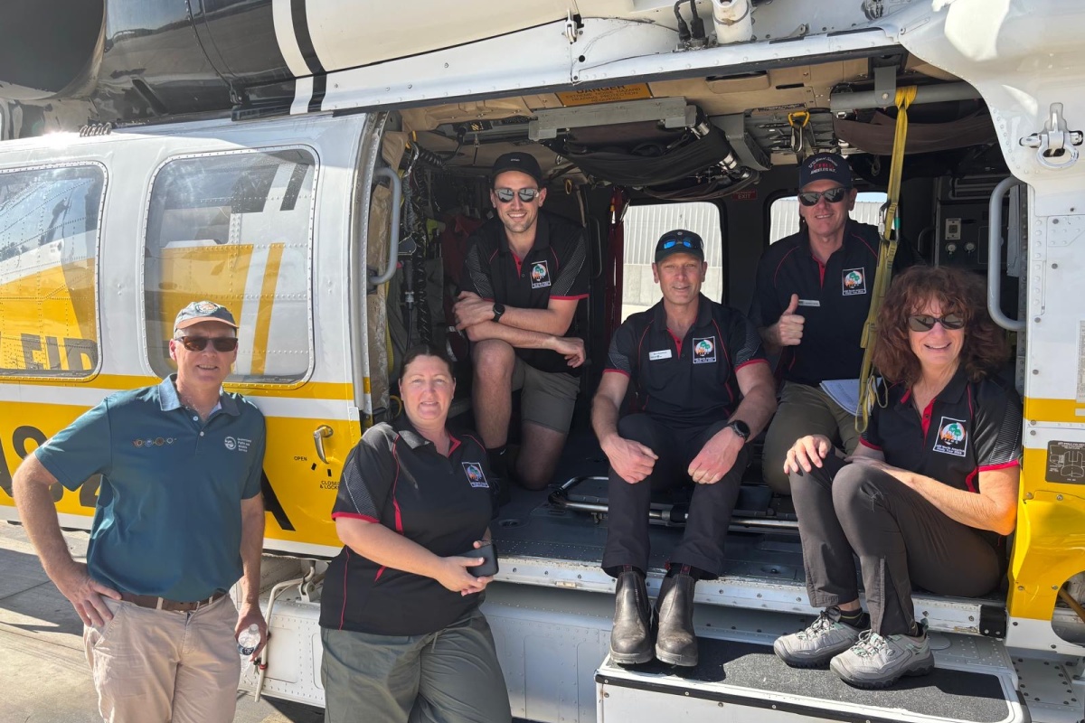 A group of firefighters pose on a helicopter