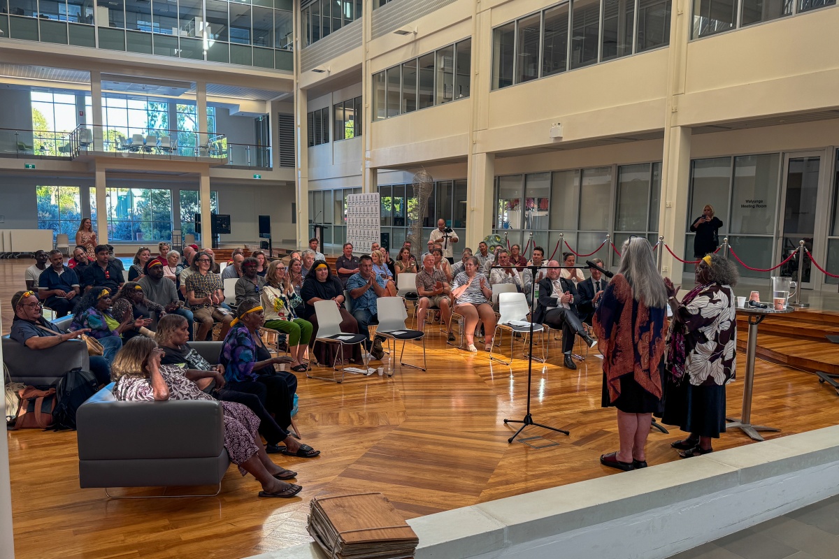 Two Aboriginal women stand in front of an audience to give a speech