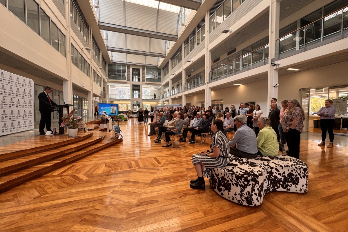 The audience listening to a man speaking at the podium in a large foyer