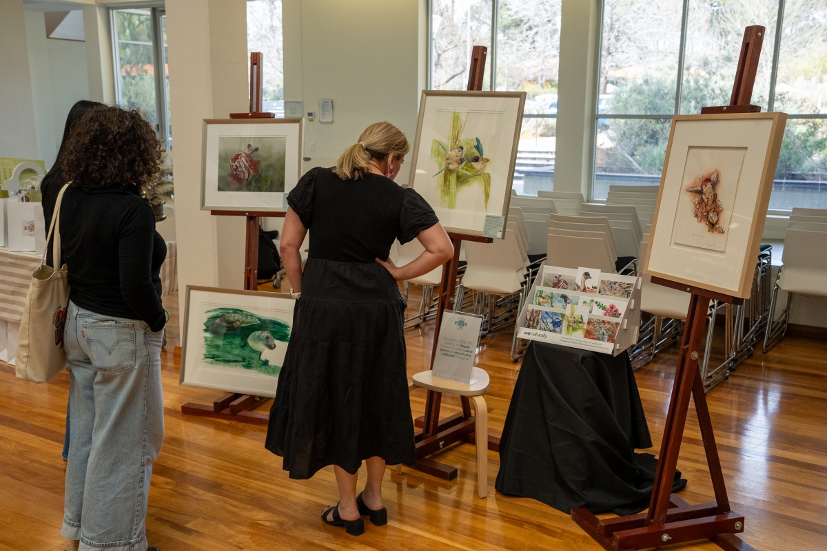 Three women admire artwork on easels