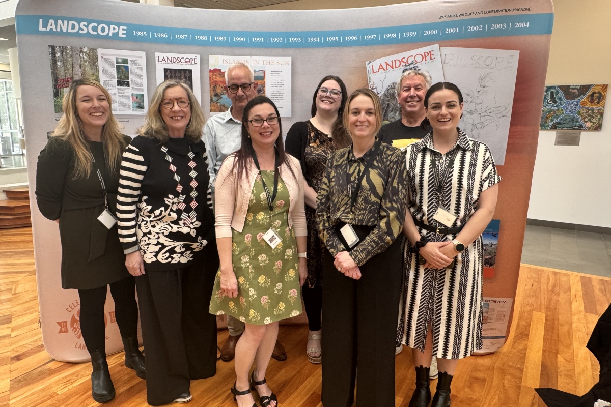 Eight people proudly stand in front of a banner display