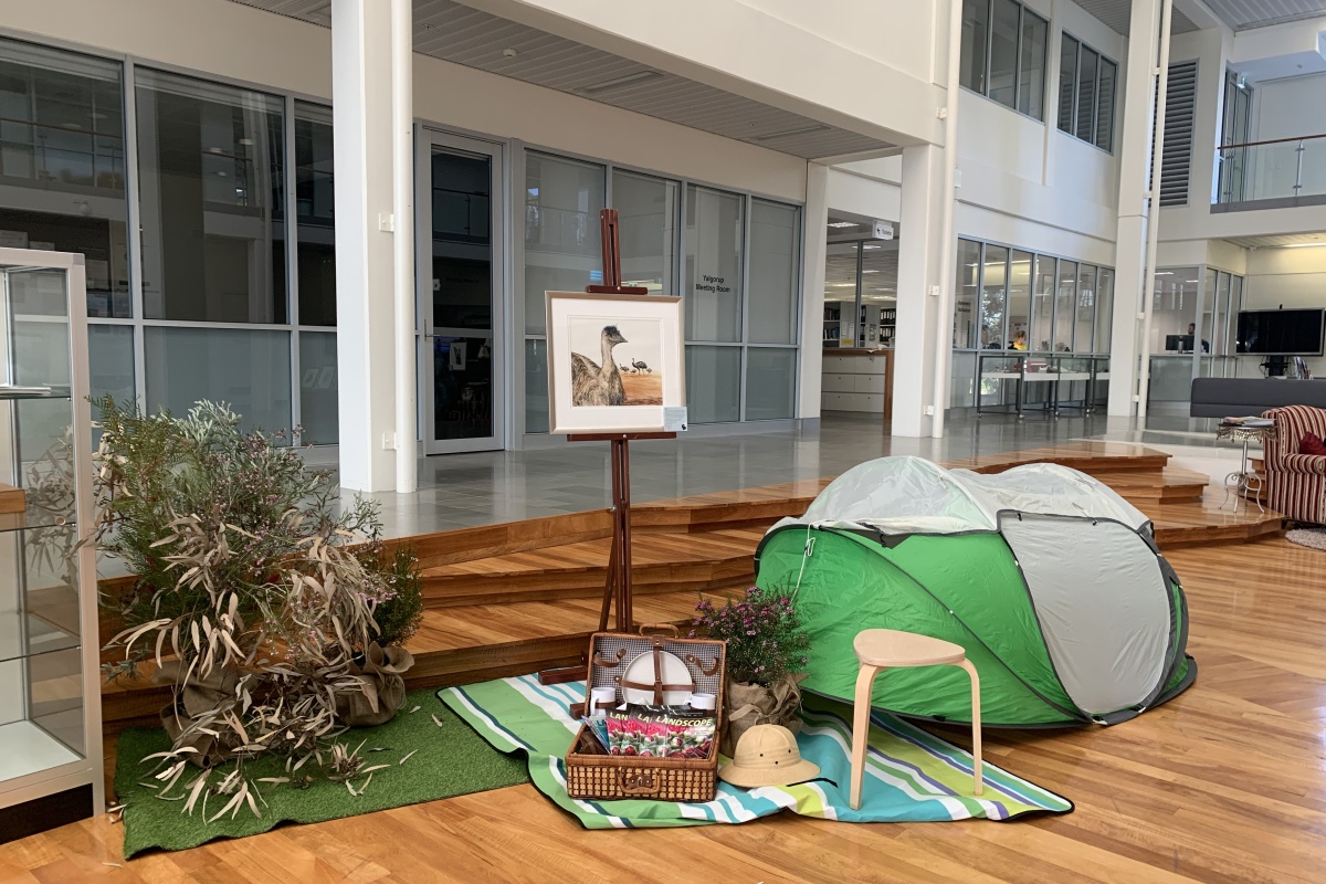 An exhibit with a tent, picnic basket, rug, and illustration