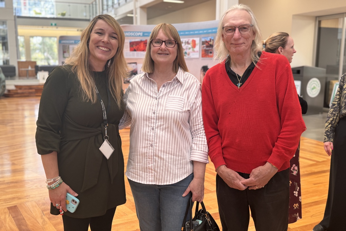 Two women and a man smile at the camera at the event