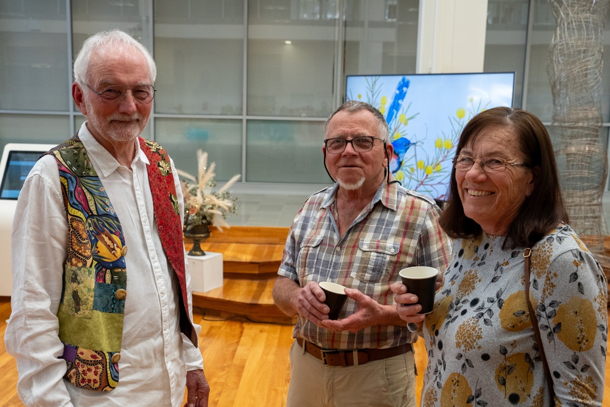 Two men and one woman smile in a foyer